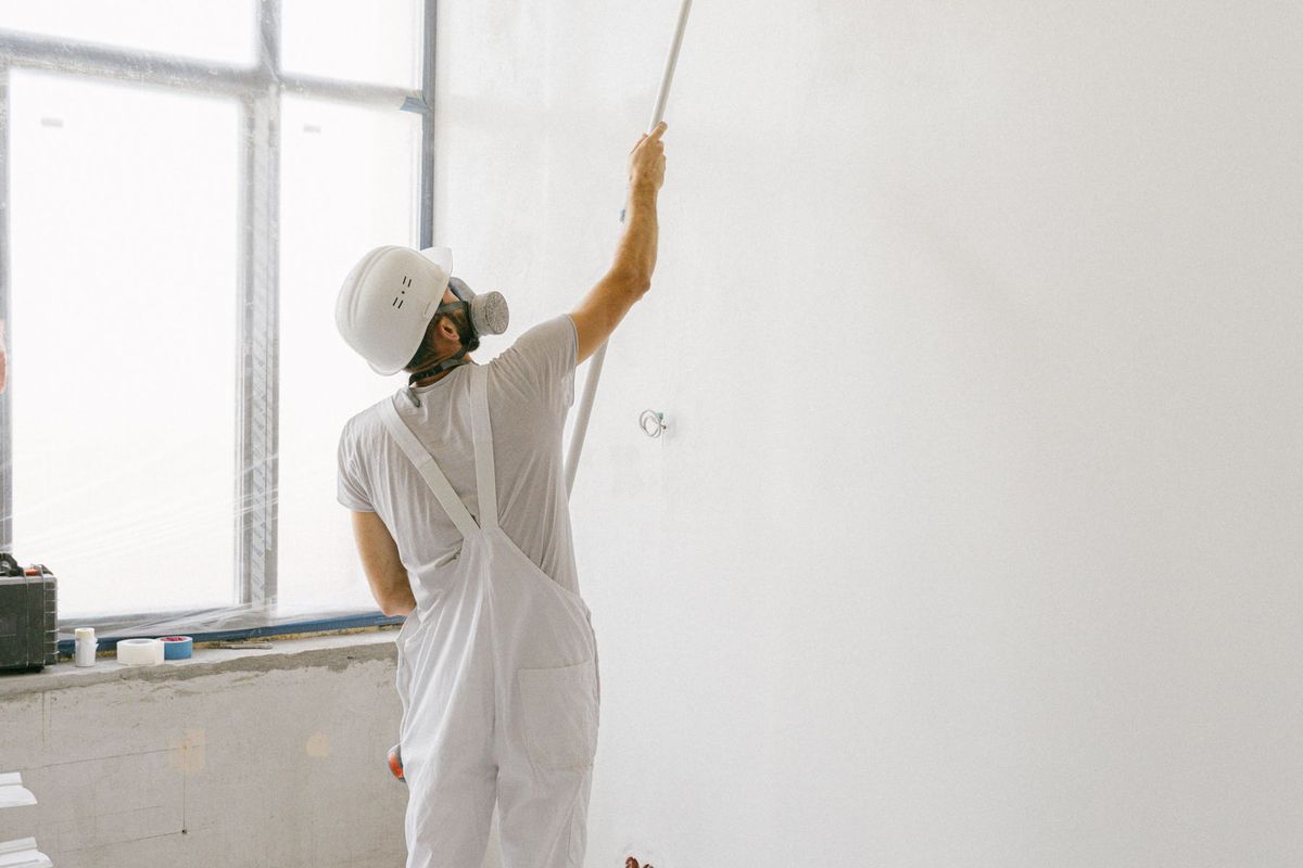 Pintor con rodillo pintando una pared blanca